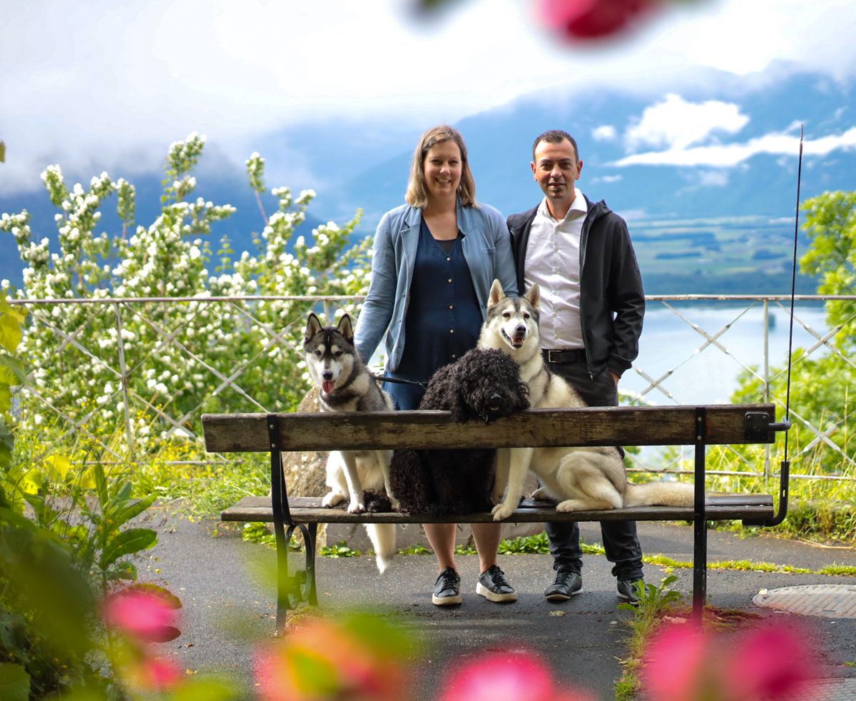 The breeders with two Siberian Huskies and a Barbet on a bench by the lake