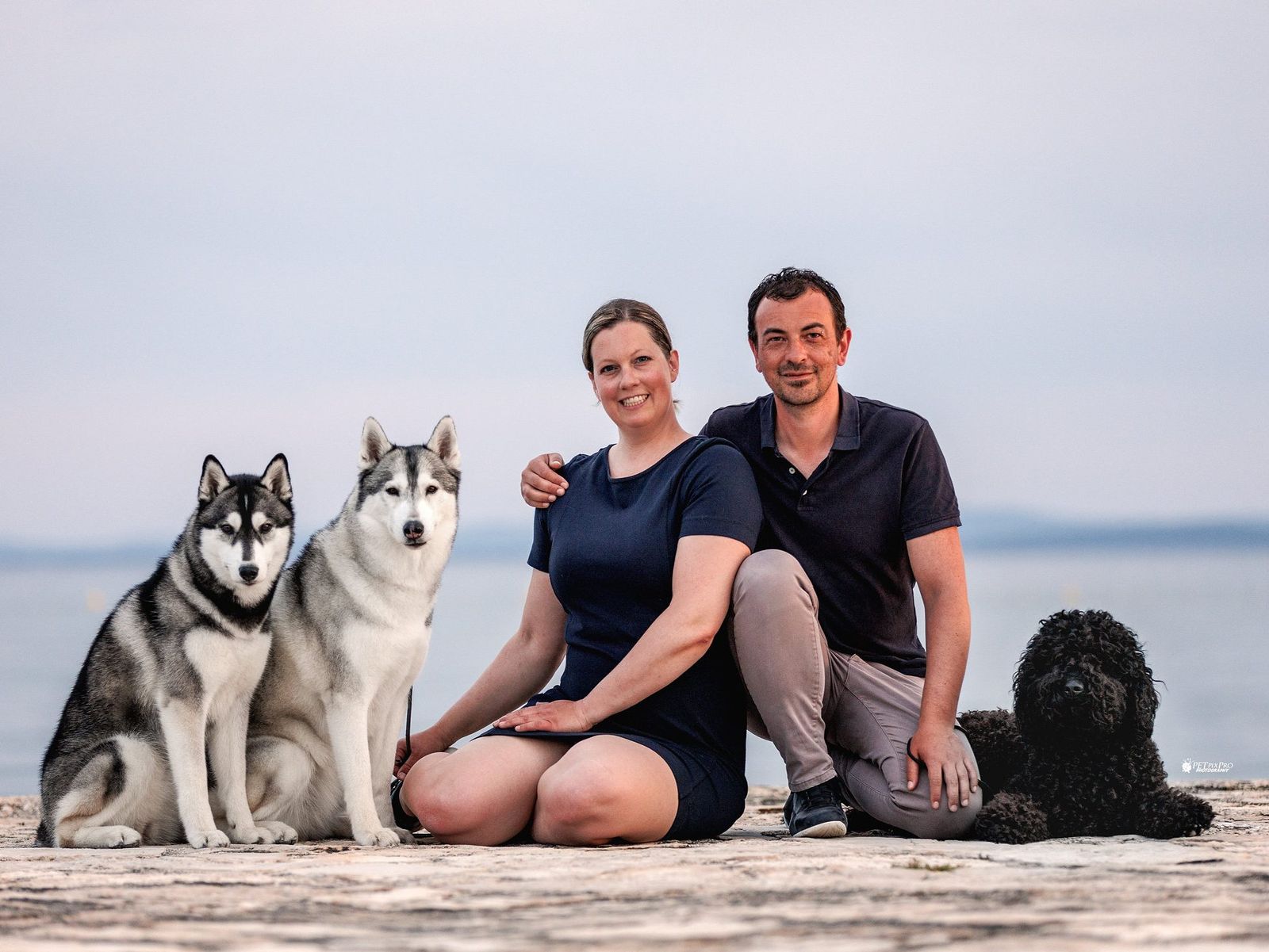 The breeders of Joiel's Palace with two Siberian Huskies and their Barbet by the sea